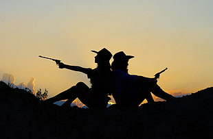 silhouette of two girls holding pistols