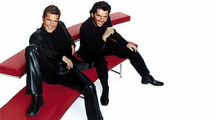 two man wearing black long sleeve top and pants sitting on red leather couch
