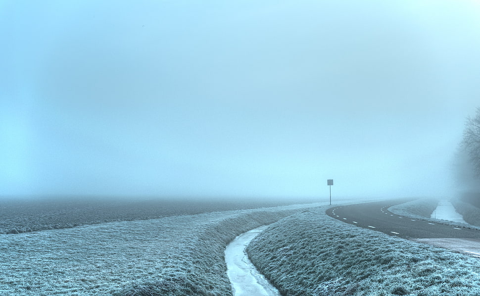 empty road beside body of water during cloudy sky HD wallpaper