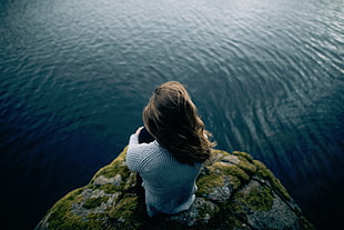 women's blond hair wearing gray sweater looking at the sea