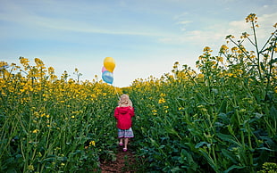 girl in red hoodie walking in the flower field