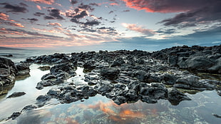 landscape photo of rocks surrounded by body of water during daytime, rocks, water, sky