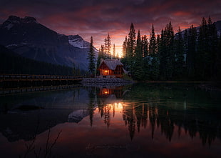 brown wooden house in the middle of lake near body of mountain HD wallpaper