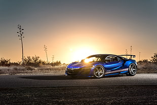 photo of blue luxury car on empty road against the sun