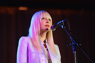 blonde haired woman standing in front of a mic