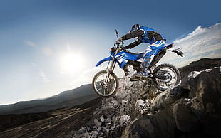 man' riding in blue and black motocross dirt bike