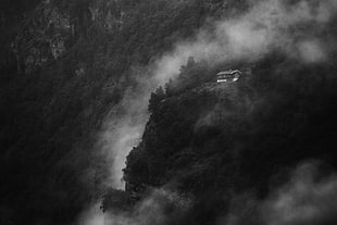 grayscale photo of house on mountain cliff