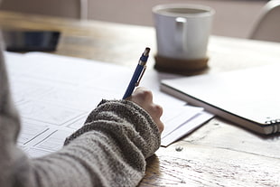 person holding click pen writing on paper