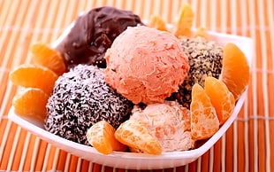 orange fruit, ice cream, and pastry on white plastic bowl