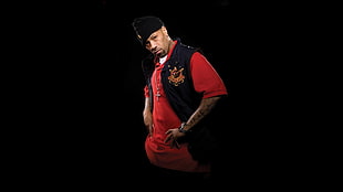 man wearing black vest, red polo shirt, and black cap