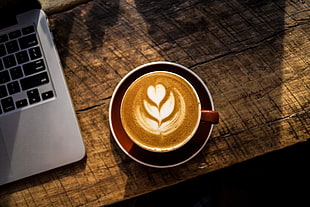 coffee on brown mug on table with red saucer