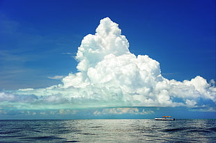 white boat on sea with view of columbus clouds