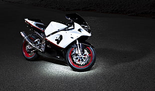 white and black sport bike on top of gray surface