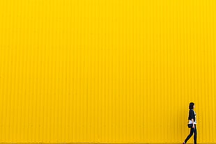 woman wearing black and white outfit in front of yellow metal wall