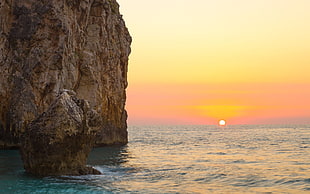 body of water beside with rock form and sunrise view HD wallpaper