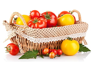 red tomato with orange fruit in brown wicker basket