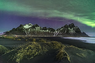 green borealis above snow covered mountaing, iceland