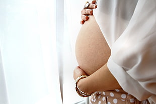 pregnant woman in brown polka dot bottoms with white blouse near the white curtain during daytime HD wallpaper