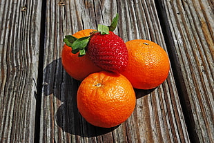strawberry on top of three Orange fruits