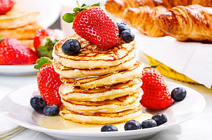 pile of pancakes with blueberries and strawberries