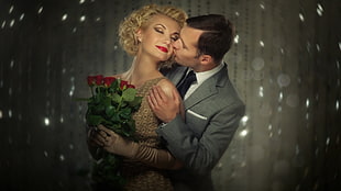 man kissing the woman holding bouquet of flowers