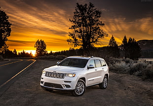 white Jeep SUV parked beside road during sunset