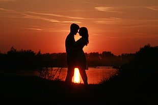 silhouette of couple standing near calm lake