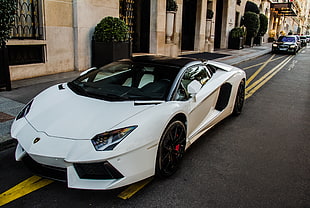 person taking photo of white Lamborghini Aventador parked near beige building during daytime HD wallpaper