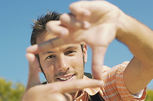 man in orange shirt doing focus hand sign