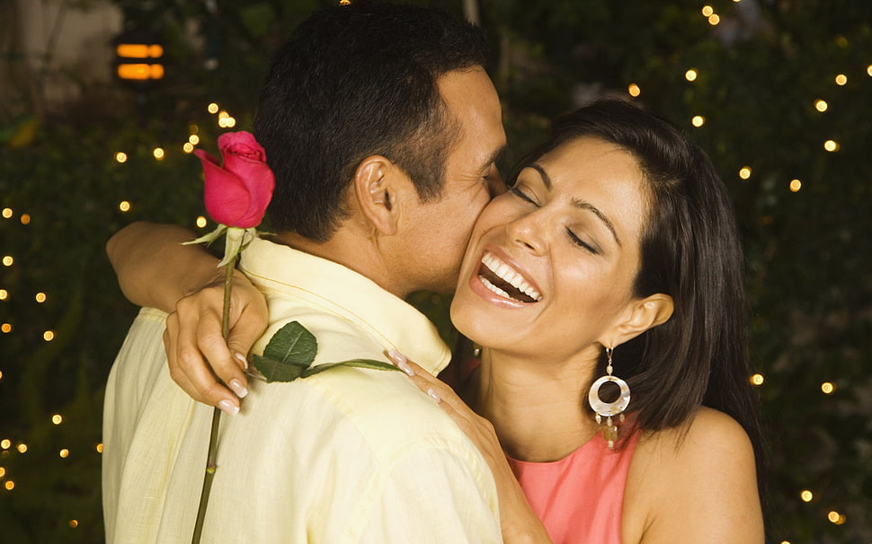 woman laughing holding red rose flower while hugging man wearing white dress shirt HD wallpaper