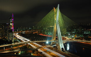 time lapse photography of highway near city high-rise buildings during nighttime