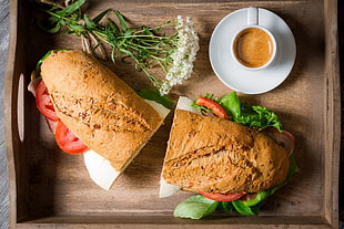 sliced vegetable sandwich beside coffee cup on brown wooden serving tray