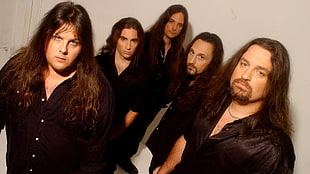 five man wearing black button-up shirt with long hairs near white wall