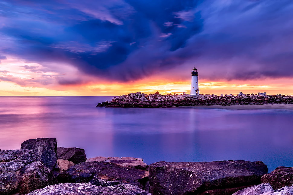 panoramic photography of white lighthouse surrounded by body of water under gray sky during golden hour HD wallpaper