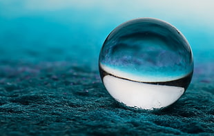clear glass ball on top of blue soil