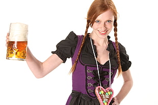 brown haired woman wearing black and purple short sleeve dress holding glass beer mug filled with brown liquid