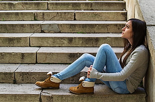 woman in gray long-sleeved shirt sitting on concrete stairs