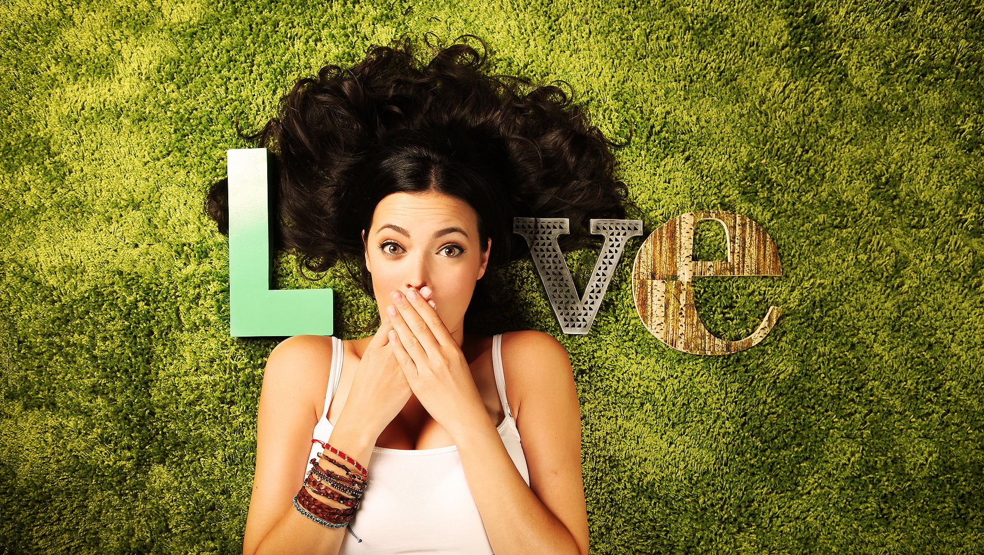 woman wearing white shirt in between cutout letter covering her mouth