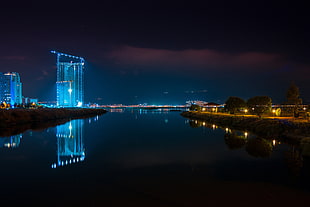 photo of body of water near lighted city during night time