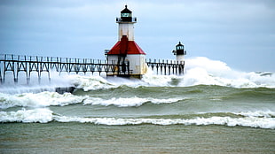 sea waves splashes to black and red lighthouse