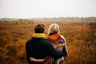 selective focus photography of man holding woman on brown grass field