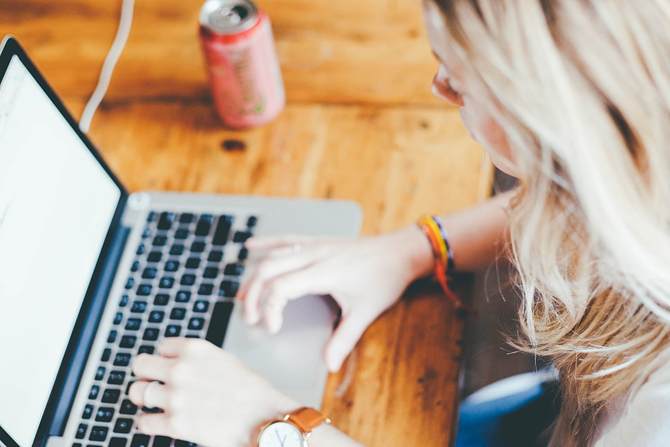 woman sitting on chair while using MacBook Pro on table HD wallpaper