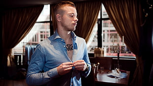 man wearing chambray dress shirt with chest tattoo standing inside room during daytime