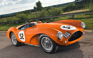 orange and white racing car on asphalt road