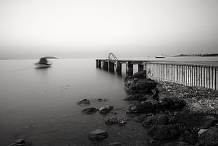 grayscale photo of docks by the sea at foggy day
