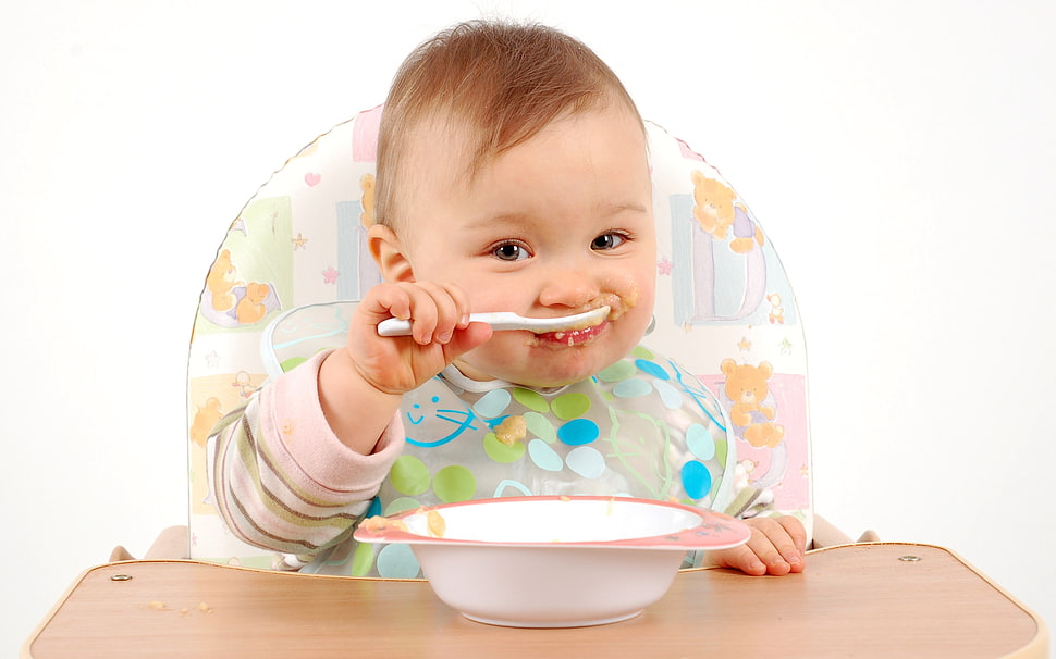 baby eating sitting on high chair HD wallpaper