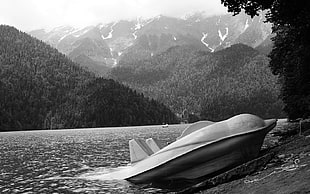 grayscale photo of boat beside river