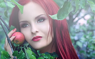 red haired woman holding a red apple