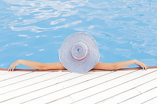 woman in white-and-blue floppy hat in swimming pool