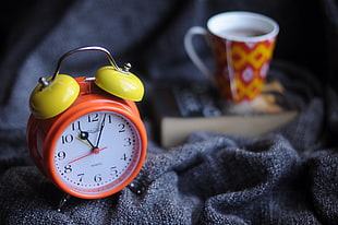 orange and yellow analog table alarm clock showing 11:03